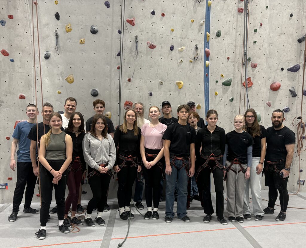 Young adults gathered in front of an indoor rock-climbing wall