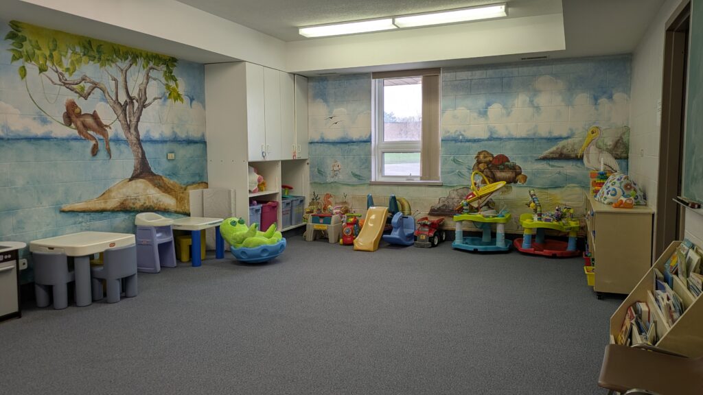 Church nursery room with a painted tree mural and play area