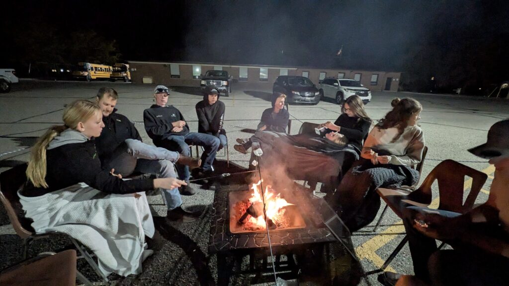Group gathered around a bonfire at an evening youth event